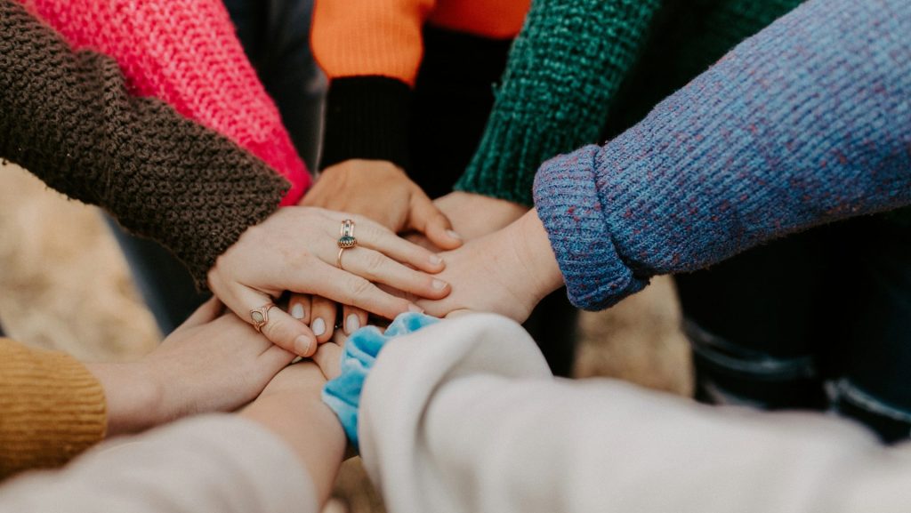 person in red sweater holding babys hand
